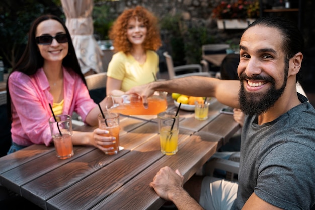 Amigos sorridentes de tiro médio com bebidas