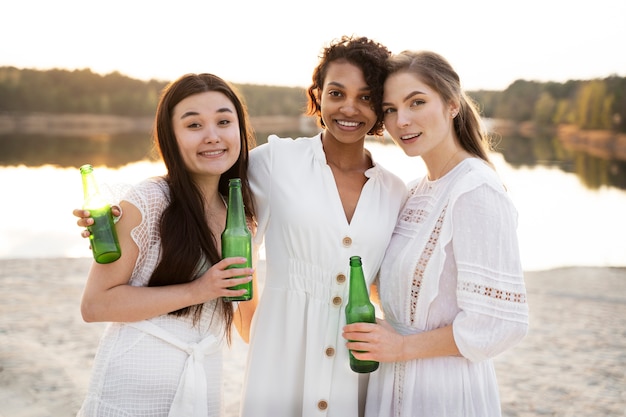 Amigos sorridentes de tiro médio com garrafas