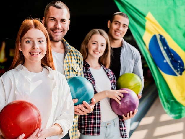 Amigos sorridentes de tiro médio jogando boliche