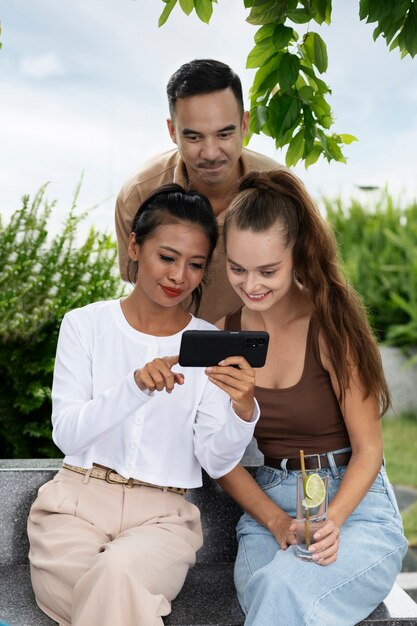 Amigos sorridentes de tiro médio olhando para o telefone