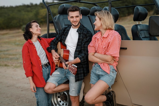 Amigos sorridentes tocando guitarra enquanto viajam de carro