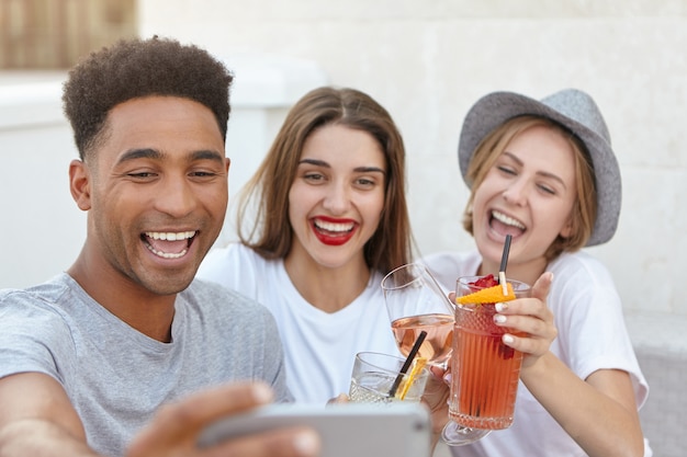 Foto grátis amigos sorrindo para a câmera do celular enquanto tiravam uma selfie