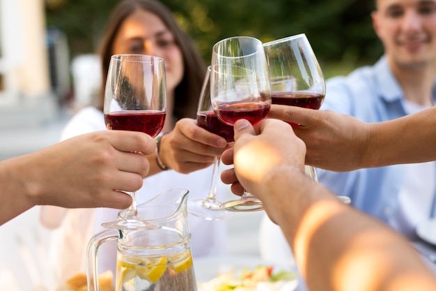 Amigos tilintando taças de vinho de perto