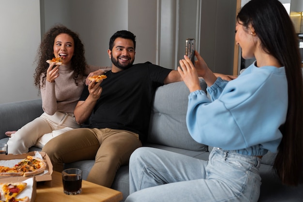 Foto grátis amigos tirando fotos enquanto comem pizza em casa