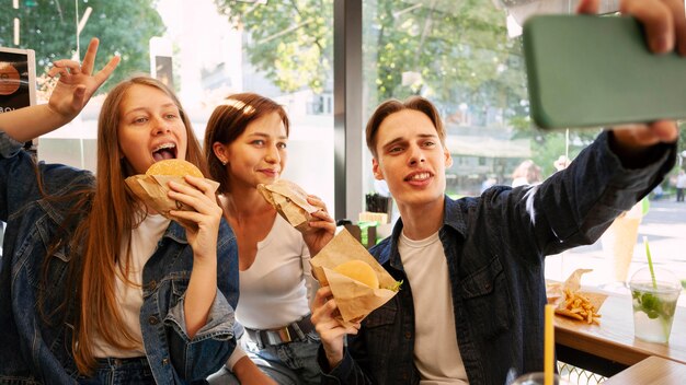 Amigos tirando selfie enquanto comem fast food