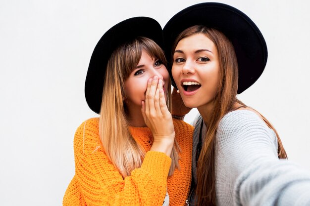 Amizade, felicidade e conceito de pessoas. Duas garotas sorridentes sussurrando fofoca em branco