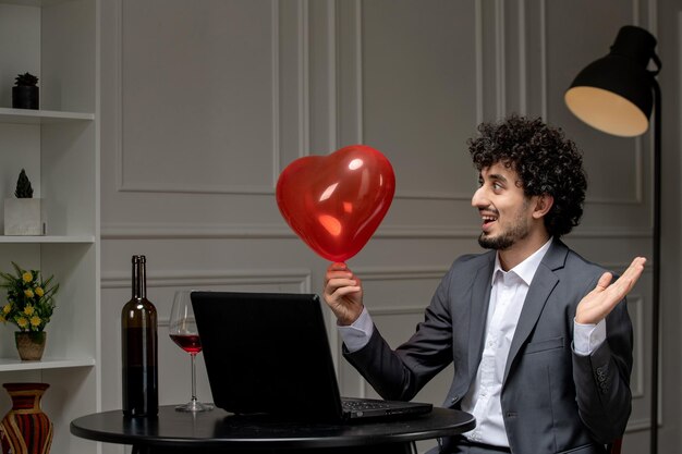 Amor virtual bonitão bonito de terno com vinho na data do computador à distância olhando para o balão do coração
