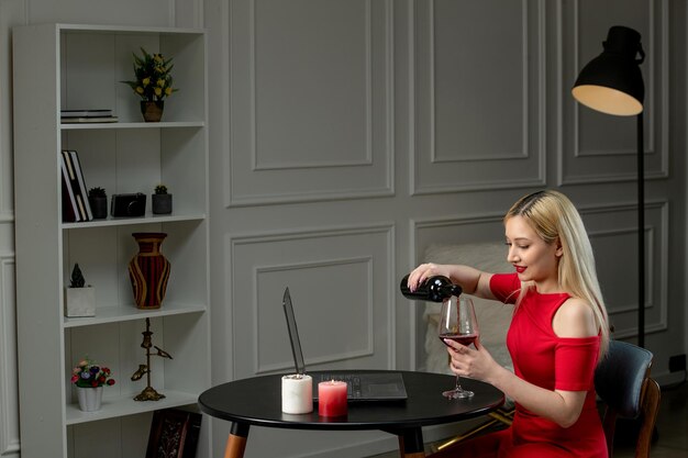Amor virtual linda garota loira de vestido vermelho na data à distância com velas derramando vinho