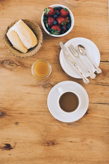 Amoras frescas; pão; geleia e xícara de café no pano de fundo texturizado de madeira