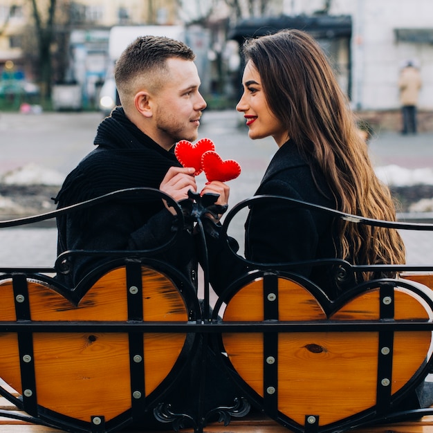 Foto grátis amoroso casal com corações vermelhos no banco