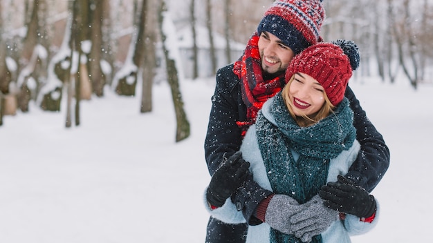 Amoroso casal feliz abraçando a queda de neve