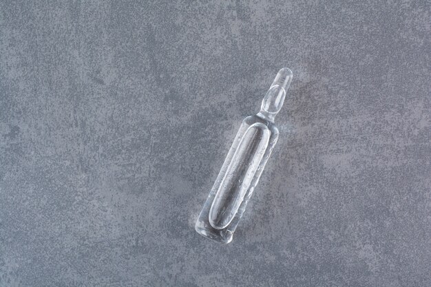 Ampola médica transparente na mesa de mármore.