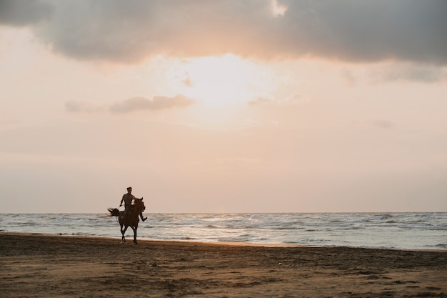 Andar a cavalo na praia ao pôr do sol