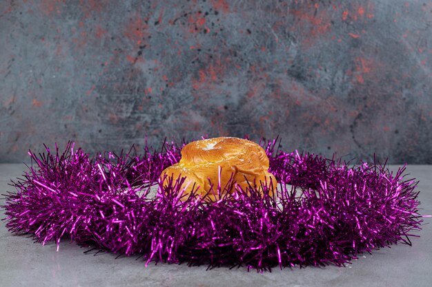Anel de enfeites roxos em torno de um pequeno pão na mesa de mármore.