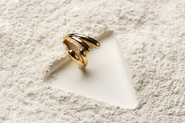 Foto grátis anel de ouro caro com fundo de pó branco