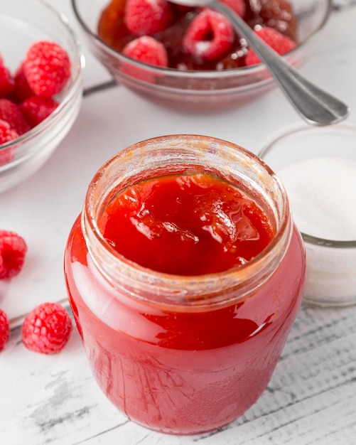 Ángulo alto de frasco de vidro com geleia de framboesa e frutas