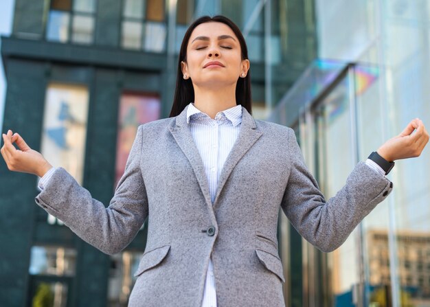Foto grátis Ângulo baixo de mulher de negócios em pose zen