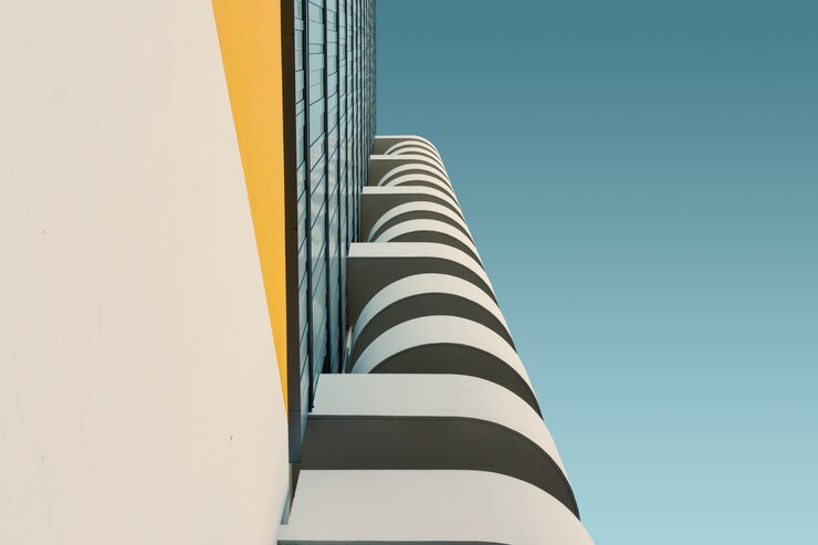 Foto grátis ângulo baixo de um edifício de concreto branco sob o céu azul claro