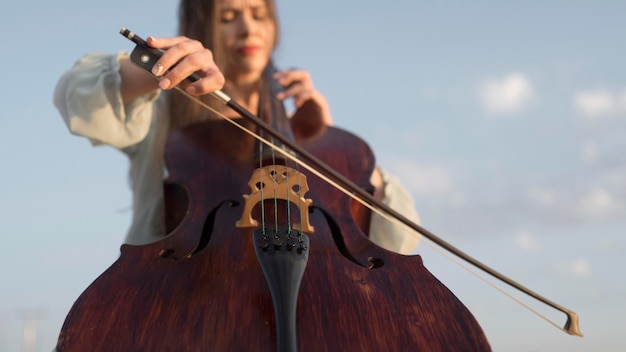 Ângulo baixo de uma musicista tocando violoncelo