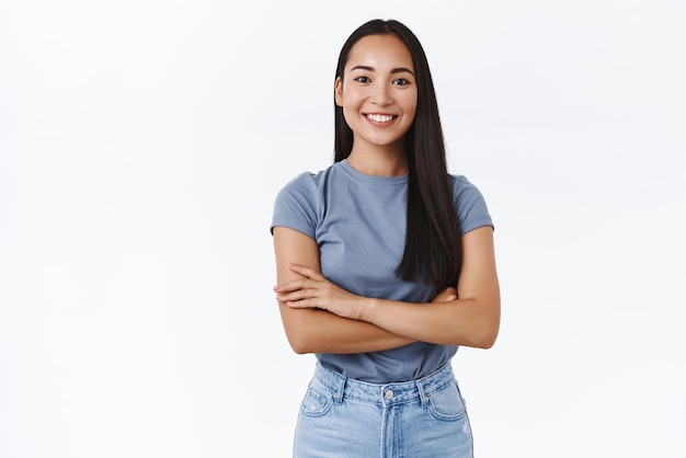 Animada, entusiasmada e determinada, sorridente, confiante, garota asiática, pronta para enfrentar qualquer tarefa, cruzar os dedos sobre o peito, assertiva, confiante, sorrindo, satisfeita, parecendo um fundo branco profissional