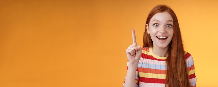 Foto grátis animada, feliz e alegre aluna ruiva, teve uma ideia, pense, responda levantando o dedo indicador eurek