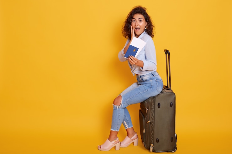 Foto grátis animado e feliz alegre jovem turista feminina sentado em sua mala grande