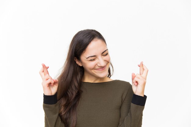 Animado feliz mulher Latina, mantendo os dedos cruzados