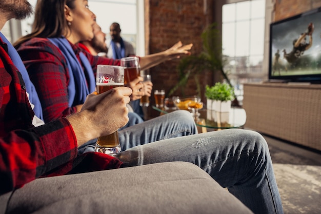 Animado grupo de pessoas assistindo futebol americano, jogo de esporte em casa.