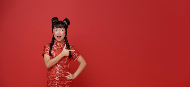 Ano novo chinês garota asiática vestindo vestido tradicional cheongsam qipao e mãos apontando dedo