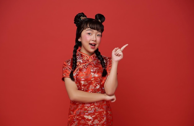 Foto grátis ano novo chinês menina asiática vestindo vestido tradicional de cheongsam qipao e dedo apontando para a mão