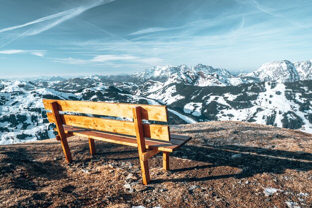 Antigo banco de madeira no topo de um penhasco com belas montanhas rochosas cobertas de neve em