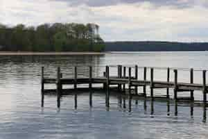 Foto grátis antigo cais enferrujado à beira do lago cercado por belas árvores em middelfart, dinamarca