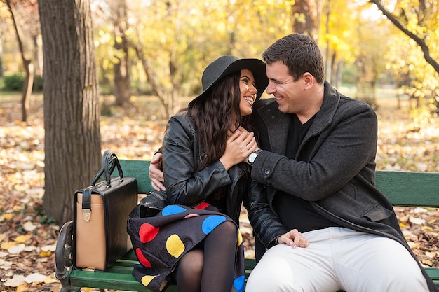 Apaixonado, feliz casal sentado em um banco no parque outono