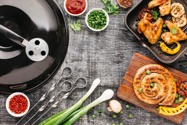 Aparelho de churrasco e carne grelhada em fundo de madeira