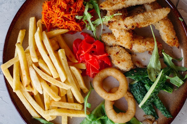 Aperitivos saborosos para grande companhia de amigos bebendo cerveja nuggets de frango dourado batatas fritas salada verde folhas e pepinos frescos Em pé na mesa branca Parecendo delicioso de dar água na boca