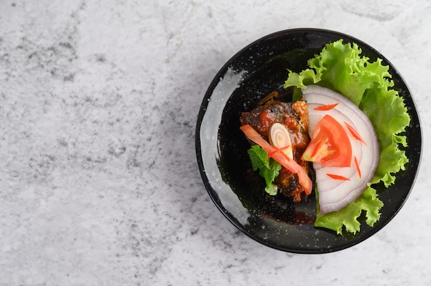 Apetitosa salada de sardinha em conserva picante em molho picante na tigela de cerâmica preta