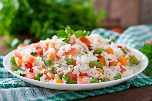 Apetitoso arroz saudável com legumes em chapa branca sobre uma mesa de madeira.