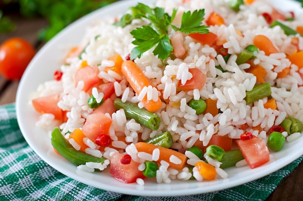 Apetitoso arroz saudável com legumes em chapa branca sobre uma mesa de madeira.