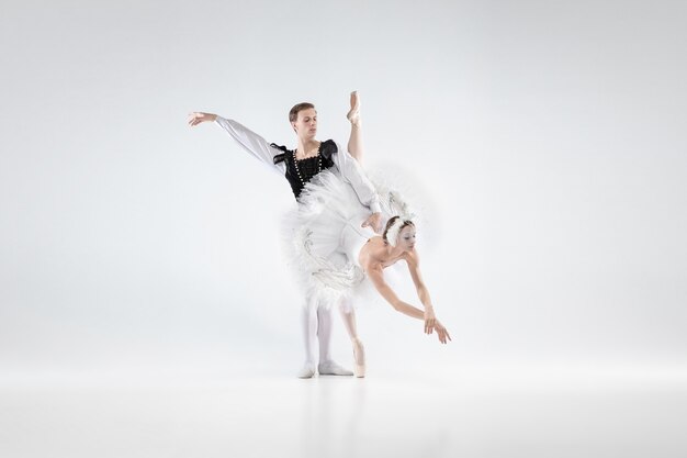 Apoiando. Graciosos dançarinos de balé clássico dançando isolado no fundo branco do estúdio. Casal com roupas macias, como personagens de um cisne branco. O conceito de graça, artista, movimento, ação e movimento.