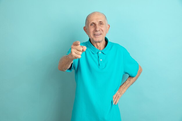 Apontando, escolhendo você. Retrato de homem sênior caucasiano no estúdio azul.