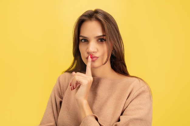 Apontando. Retrato de jovem mulher branca isolada em amarelo