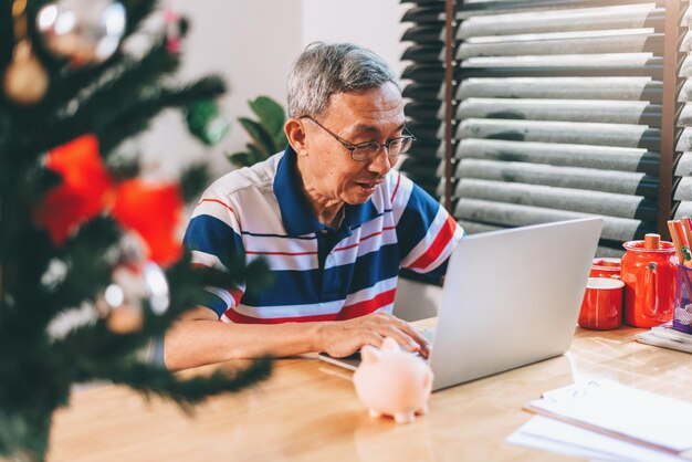 Aposentado sênior asiático usando laptop na sala de estar de casa para trabalho e reunião de conferência com amigos em situação de 19 covid