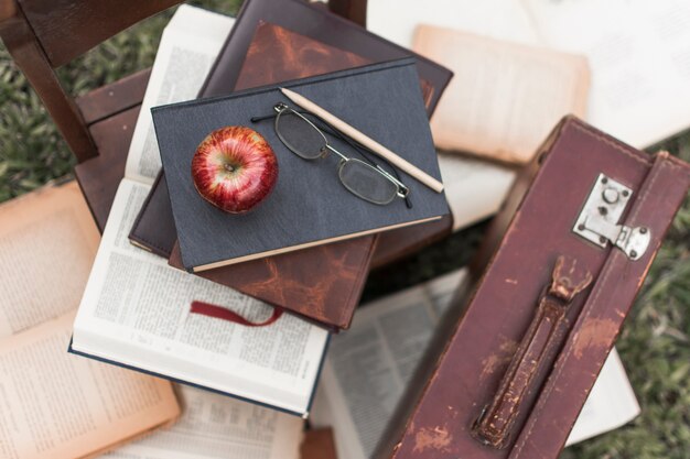 Apple e óculos em livros perto de mala