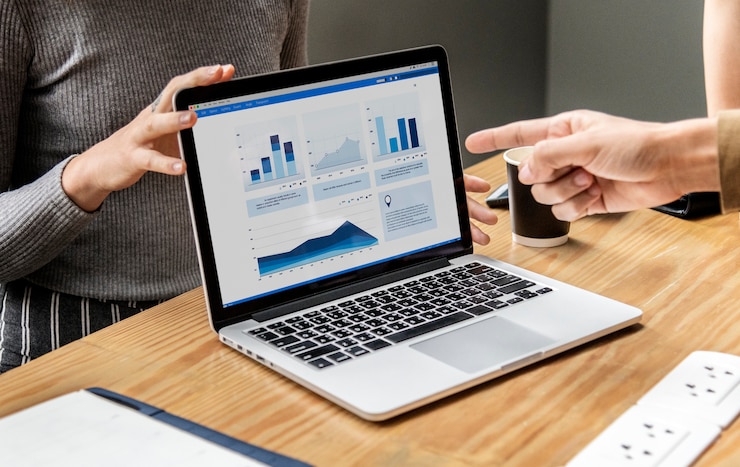 Mão apontando para gráficos no notebook demonstrando diferenças entre Power BI e Excel