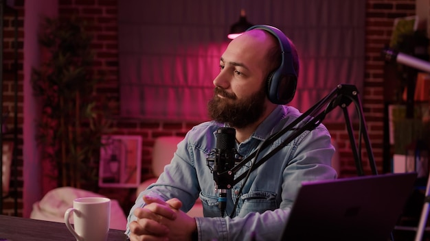 Foto grátis apresentador de talk show de rádio online pausando a conversa com o convidado para atender a chamada ao vivo do ouvinte no home studio. closeup de podcast de gravação de homem usando microfone e equipamento de áudio profissional.