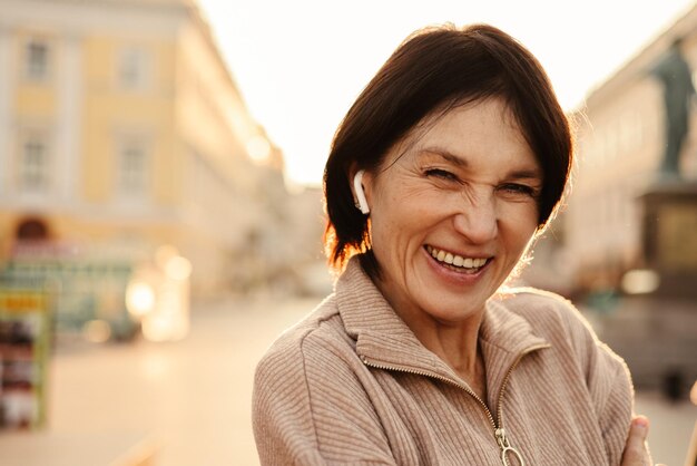 Aproximação de uma mulher adulta feliz sorrindo com os dentes no fundo desfocado da expressão facial do conceito de emoção da cidade