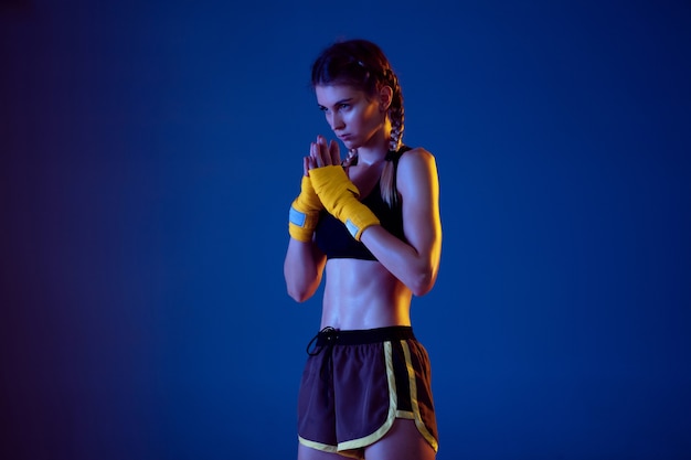 Foto grátis apta a mulher caucasiana em sportswear boxe sobre fundo azul em luz de néon.