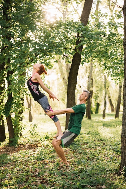 Apto casal fazendo equilíbrio de acroyoga no parque