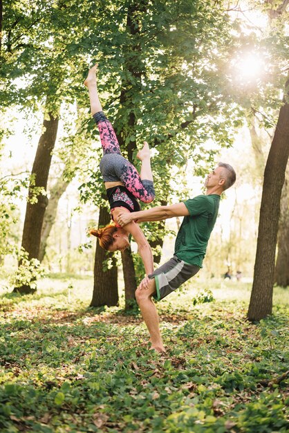 Apto meados casal adulto fazendo equilíbrio de acroyoga na natureza