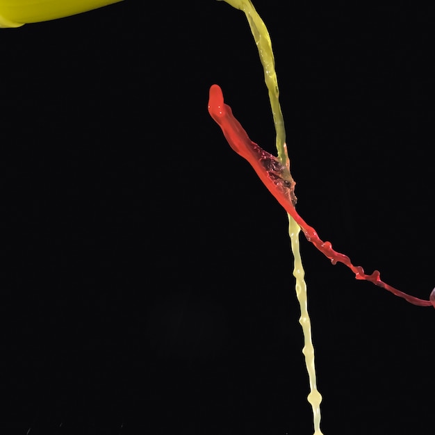 Aquarela amarela e vermelha, cruzando-se em fundo preto